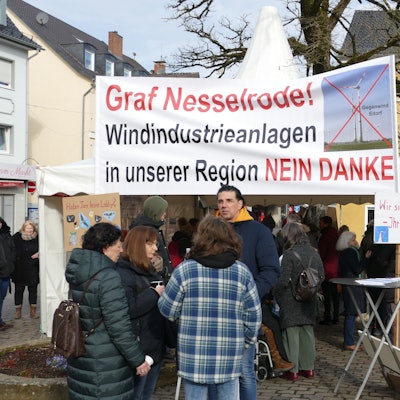 Gegner der rund um Eitorf geplanten Windkraftanlagen stehen mit Transparenten auf dem Eitorfer Marktplatz.