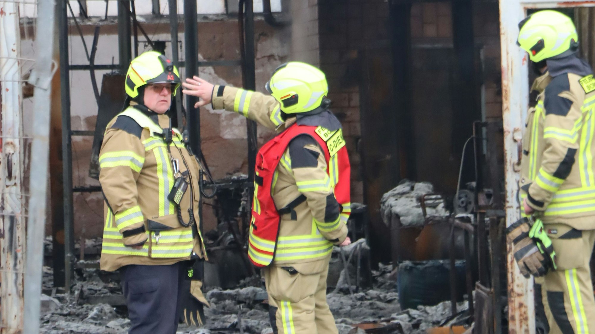 Feuerwehrleute am Halleneingang. Noch kann zur Brandursache nichts gesagt werden.
