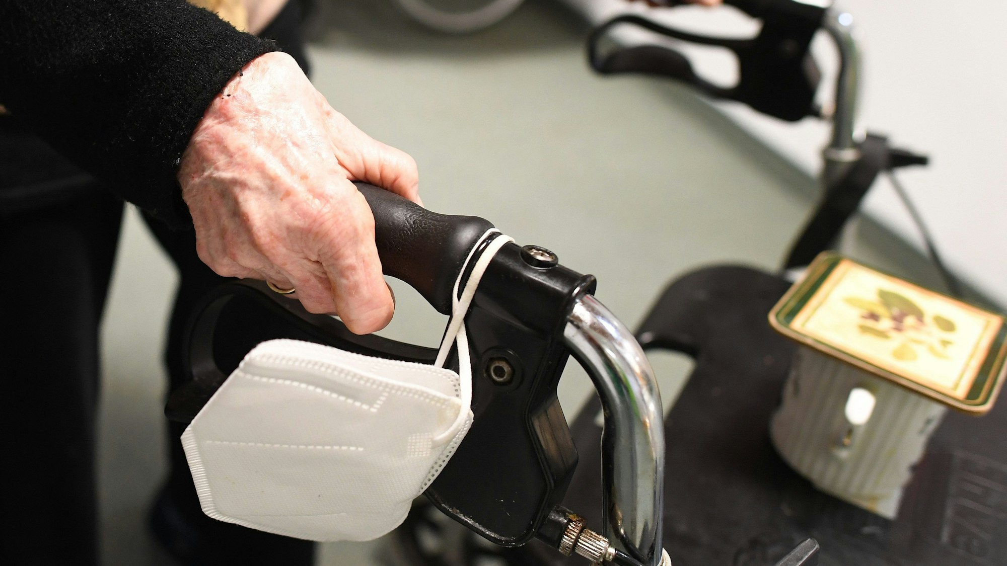 Eine Heimbewohnerin schiebt ihren Rollator mit FFP-2 Maske durch einen Gang in einem Altersheim. (Archivbild)