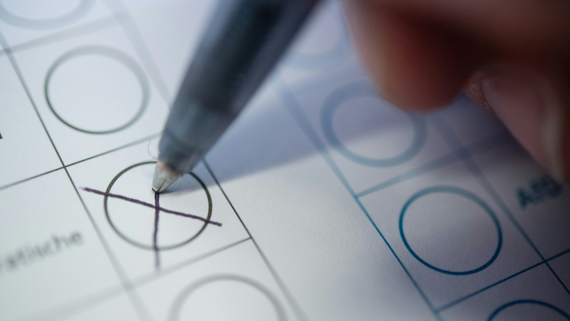 Eine Person macht ein Kreuz auf einem Wahlzettel.