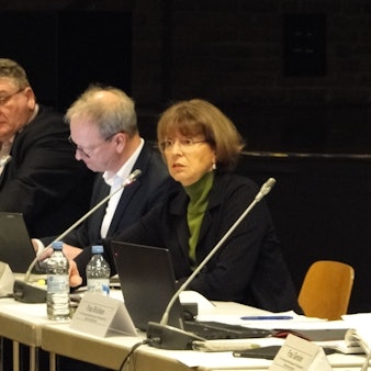 An einem langen Tisch sitzen mehrere Personen, darunter Kölns OB Henriette Reker.