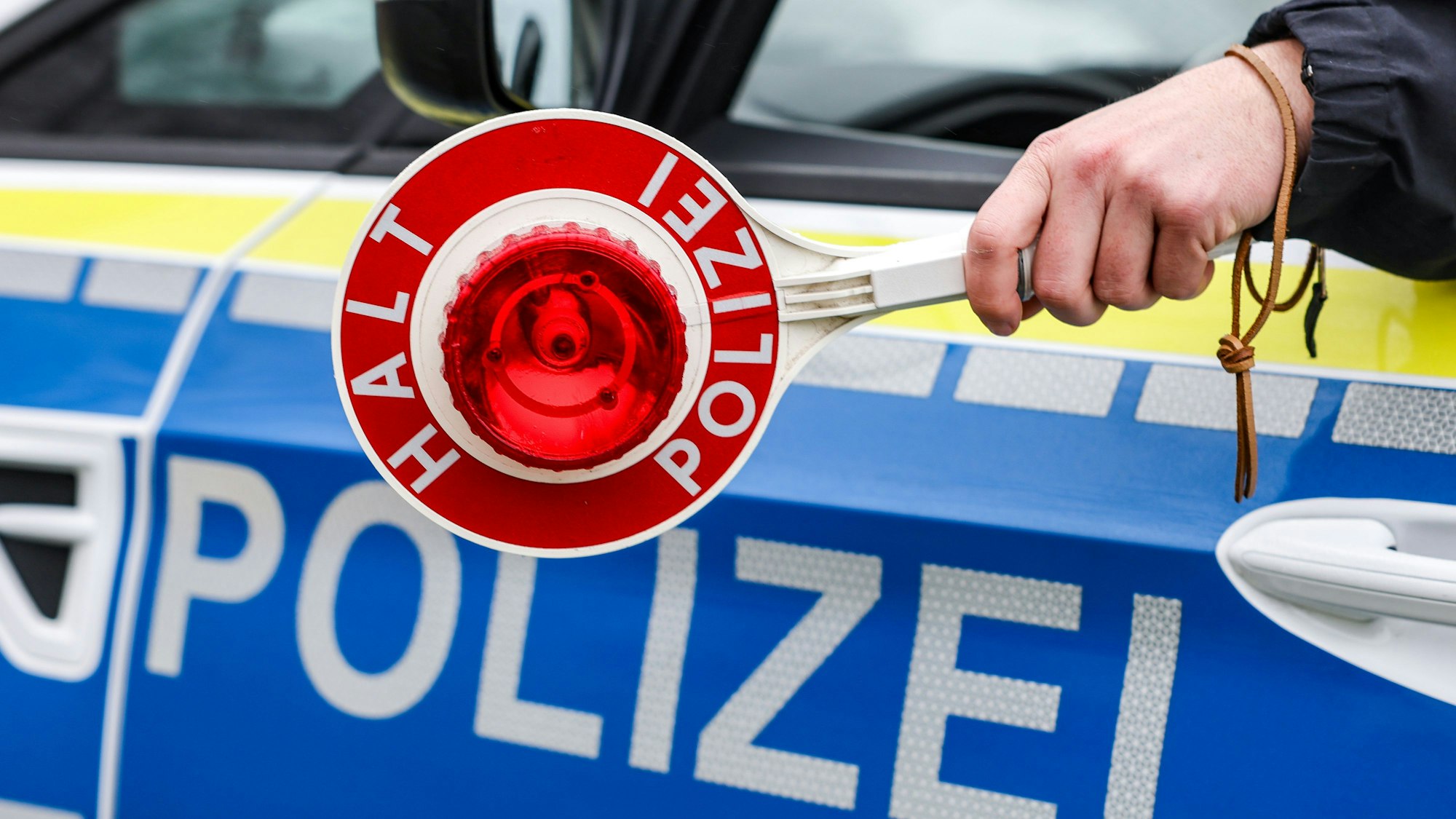 Ein Polizist hält eine Polizeikelle für eine Kontrolle.