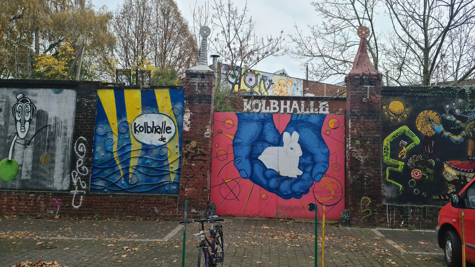 Eine Mauer ist mit bunten Graffiti beschmiert, zwei mal ist auch der Name Kolbhalle zu lesen.