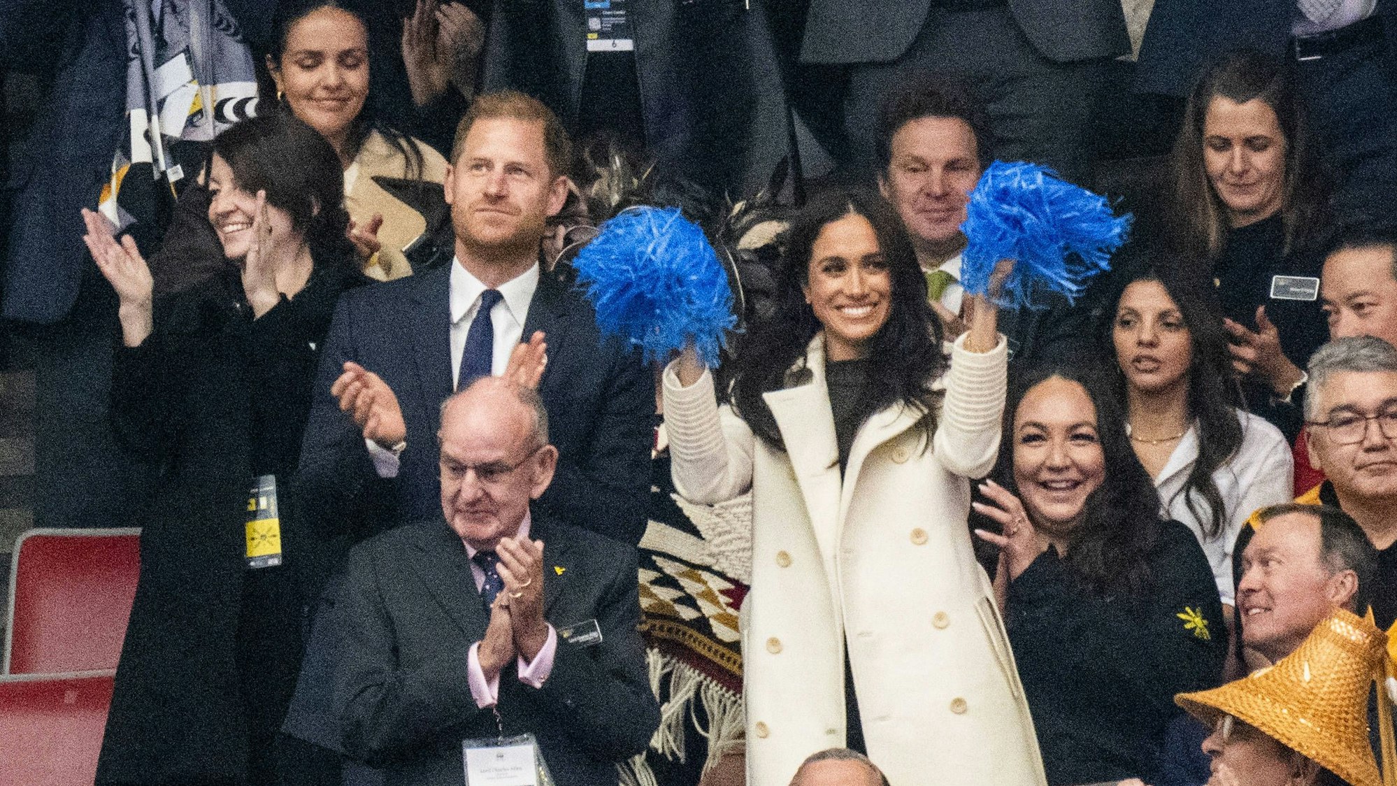 Herzogin Meghan winkt neben Prinz Harry mit blauen Pompons und feuert die Teilnehmer der Invictus Games begeistert an.