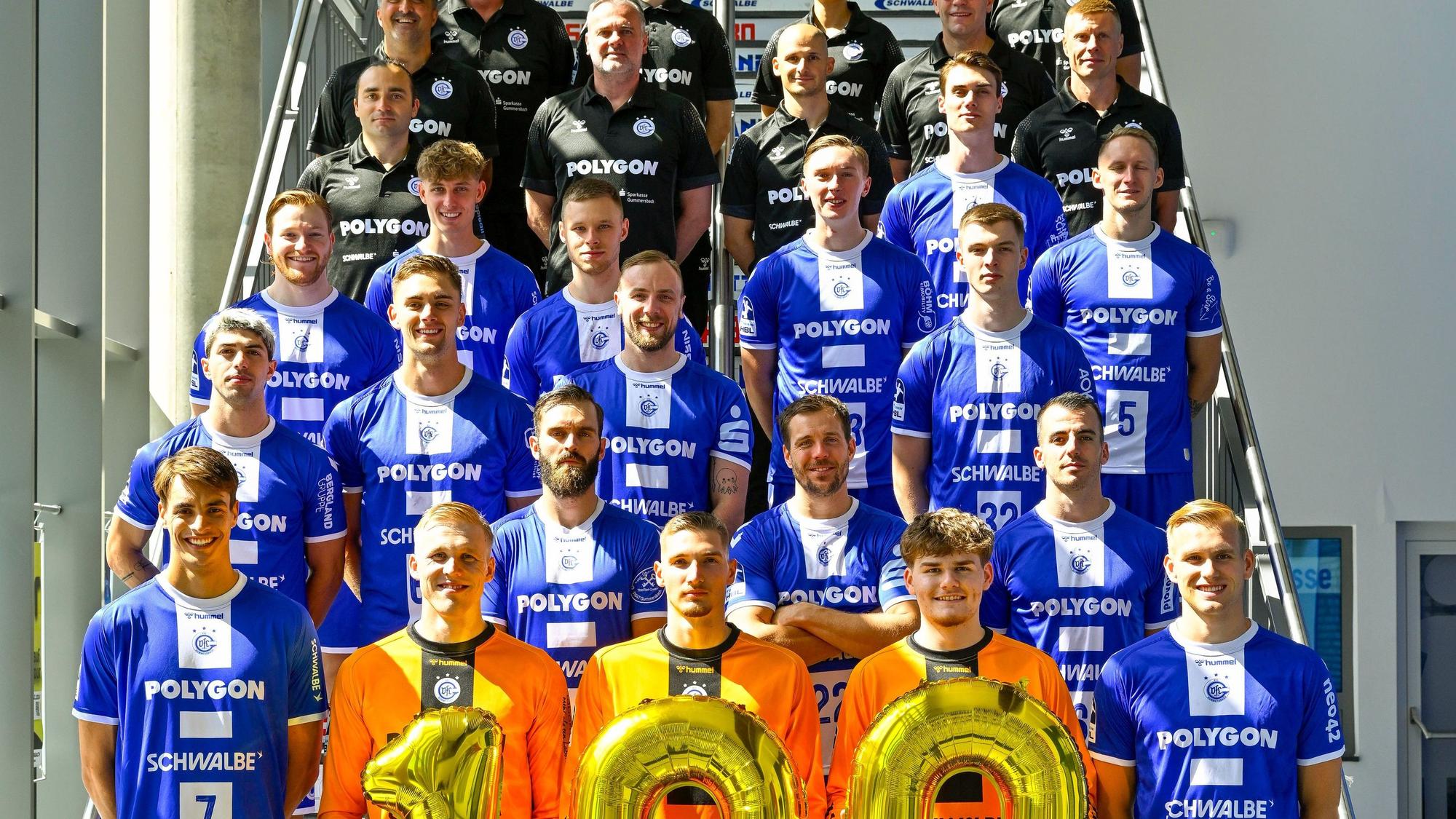 Zum Saisonstart haben sich die Handballer des VfL Gummersbach auf der Treppe aufgestellt, die drei Torwarte halten die 100.