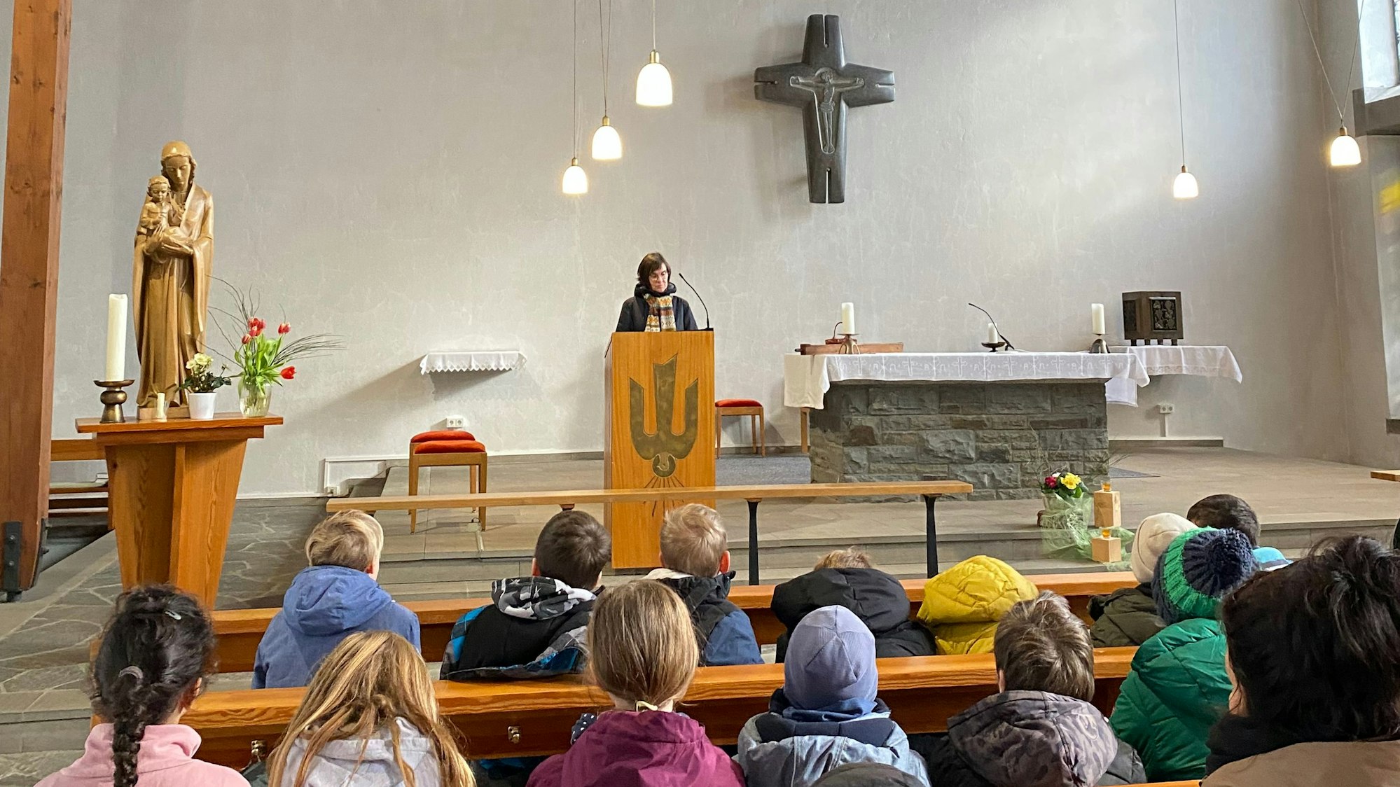 Mehrere Kinder sitzen in den Sitzbänken in einer Kirche.