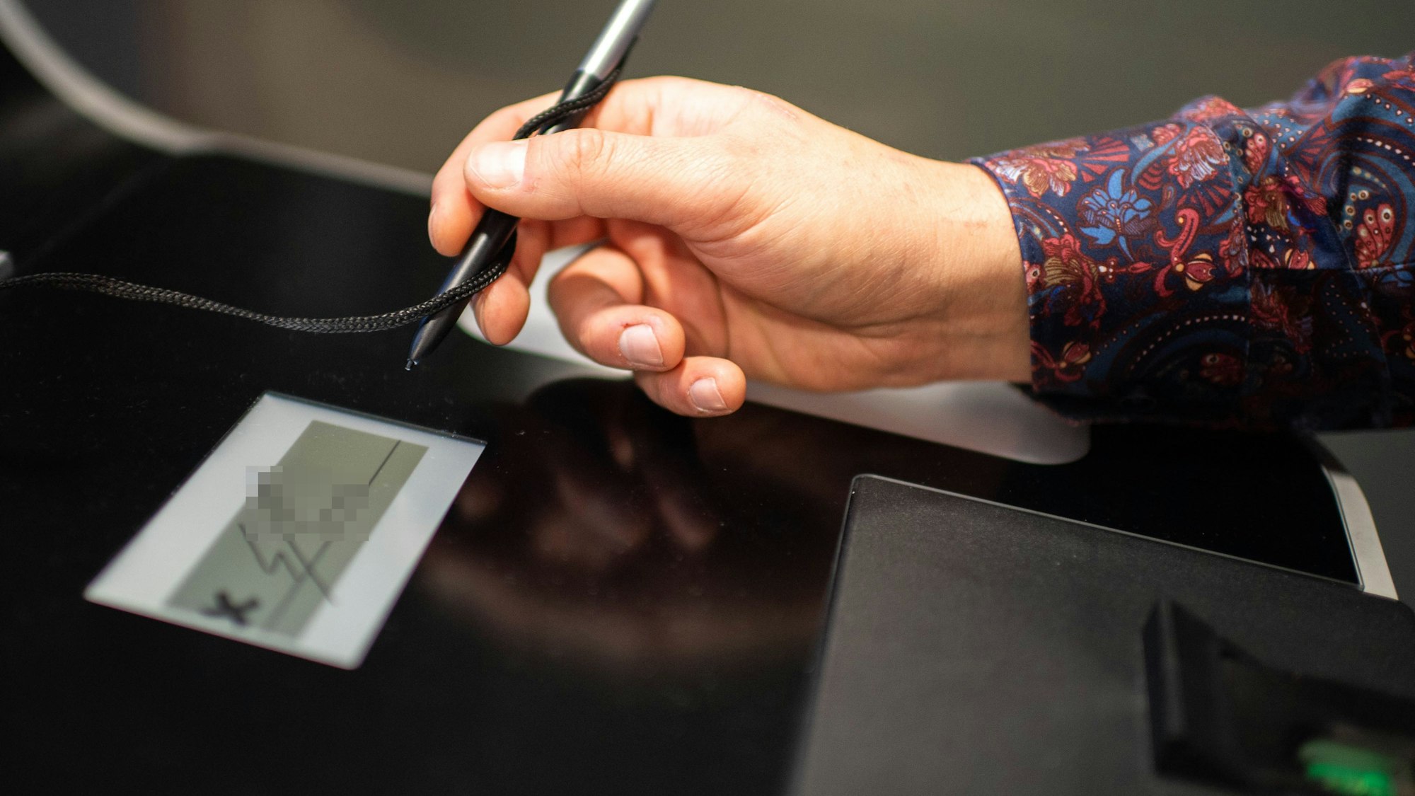 Das Bild zeigt einen Mann, der eine Unterschrift an dem Automaten macht.