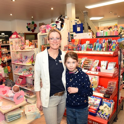Eine Frau steht mit ihrer kleinen Tochter in einem Schreibwarenladen.