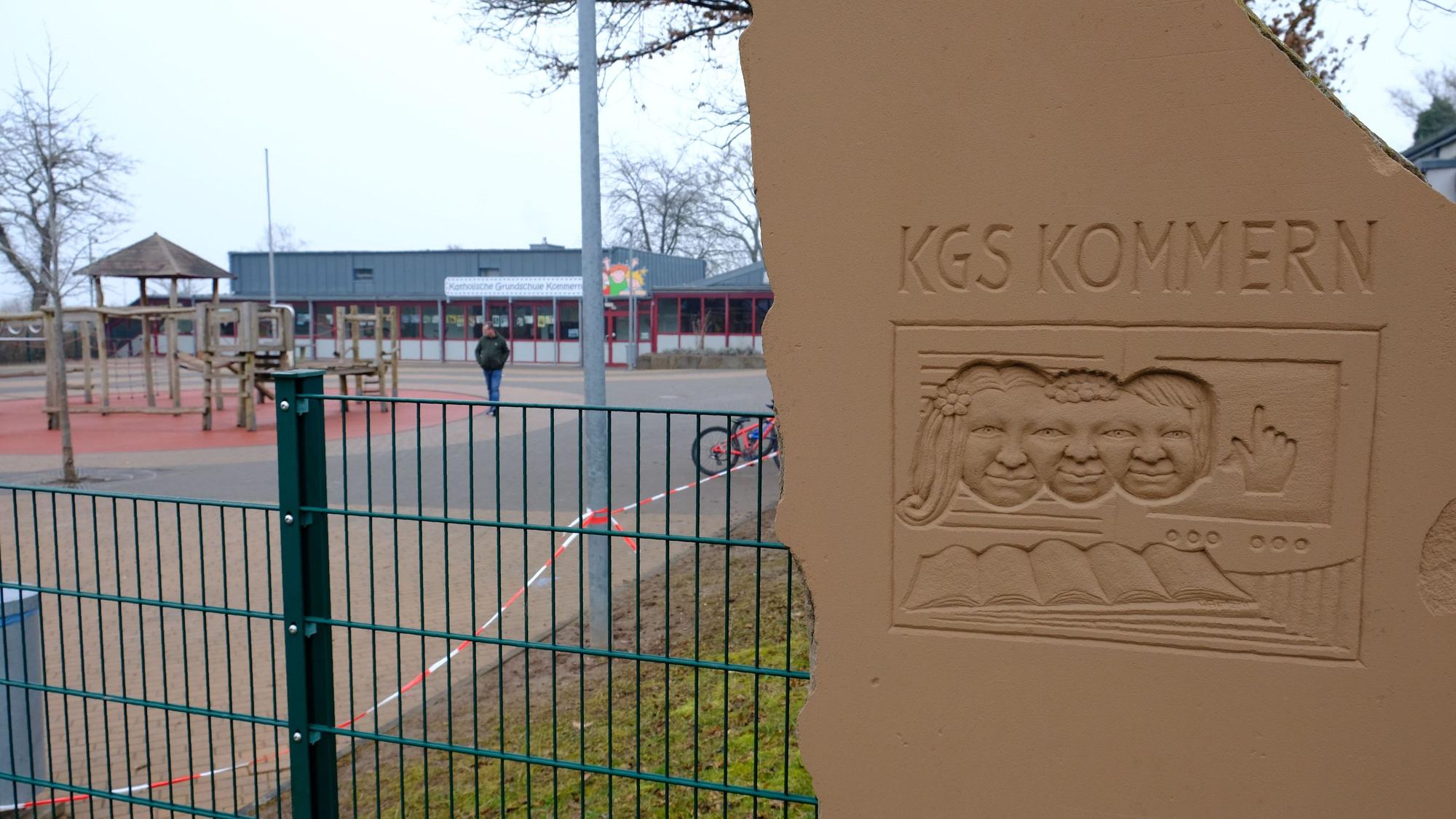 Neben dem Eingang zum Pausenhof der Katholischen Grundschule Kommern steht eine Sandsteinplastik mit der Aufschrift KGS Kommern.