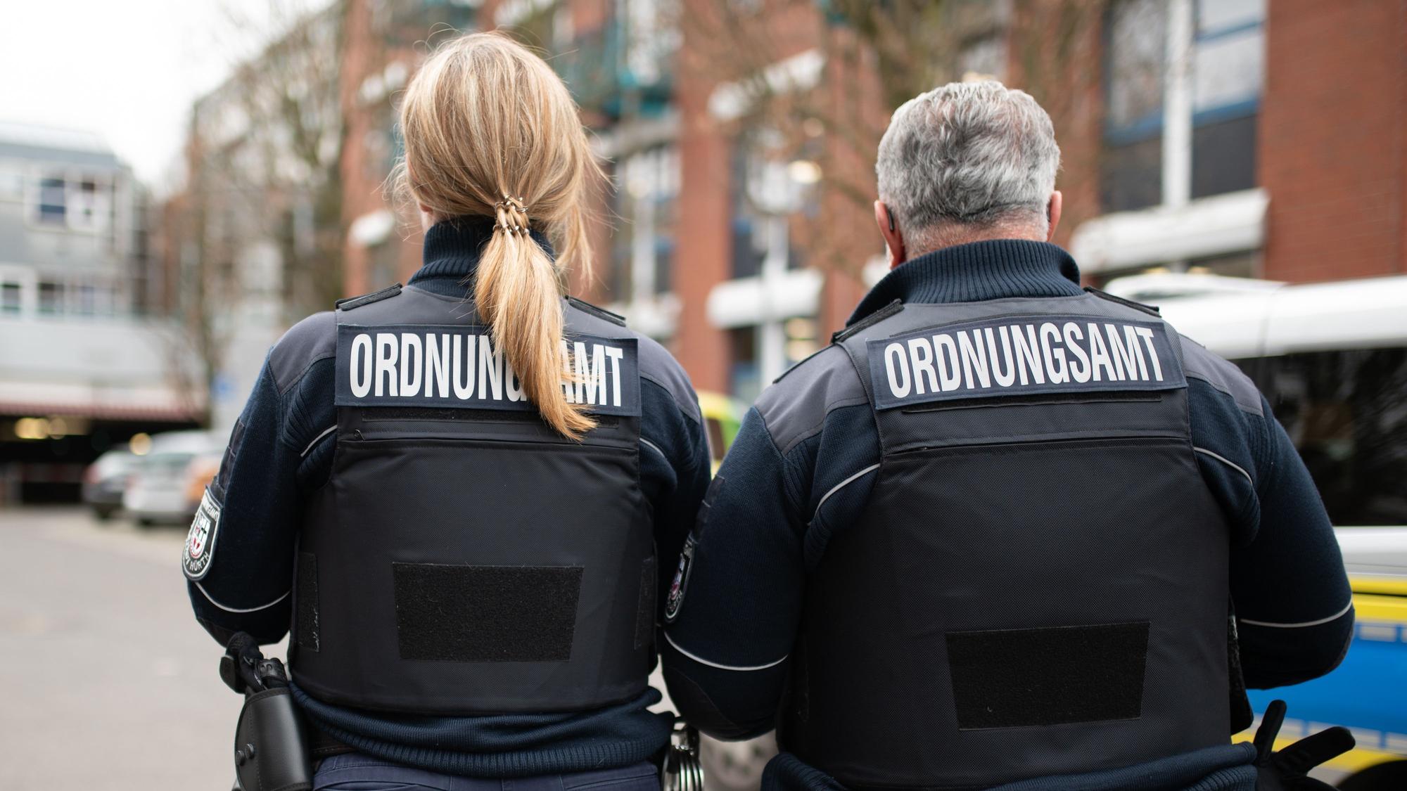 Das Foto zeigt zwei Beschäftigte des Kommunalen Ordnungsdienst mit der Aufschrift „Ordnungsamt“ hinten auf der Jacke.