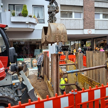 Ein roter Bagger neben einer Baugrube
