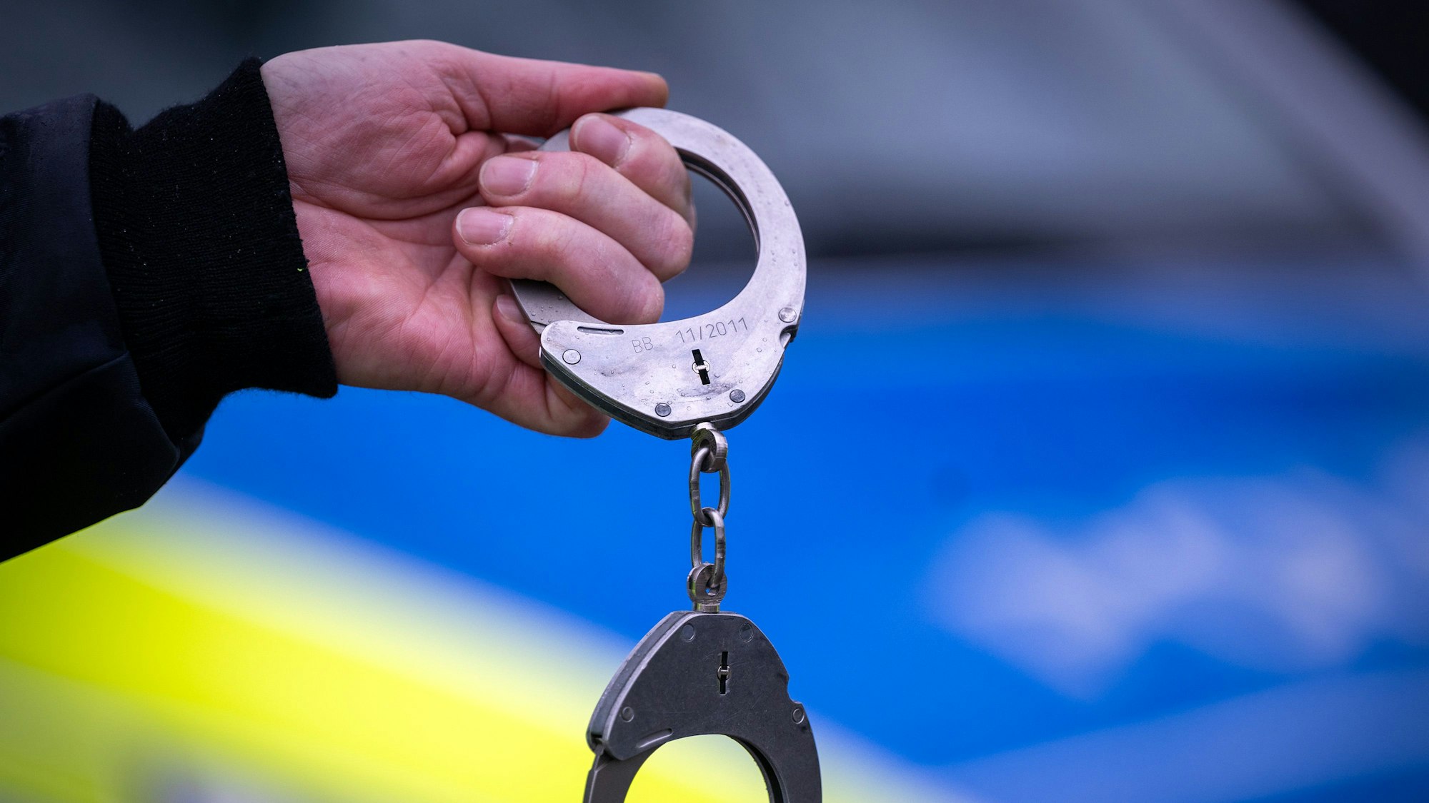 Ein Polizist hält während einer Kontrolle ein Paar Handschellen. (Symbolbild)
