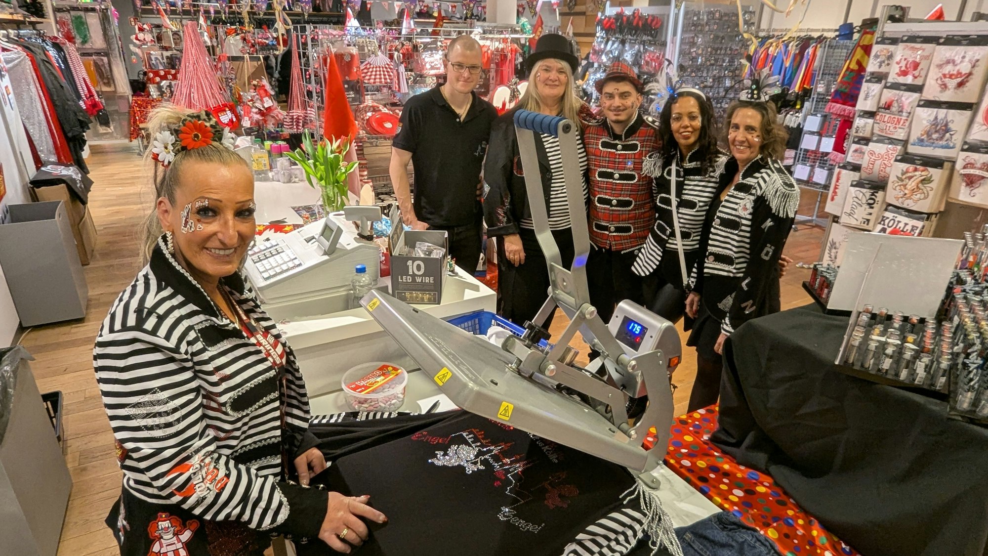 Tine Weckop an der Bügelpresse, dahinter ihr kostümiertes Team.