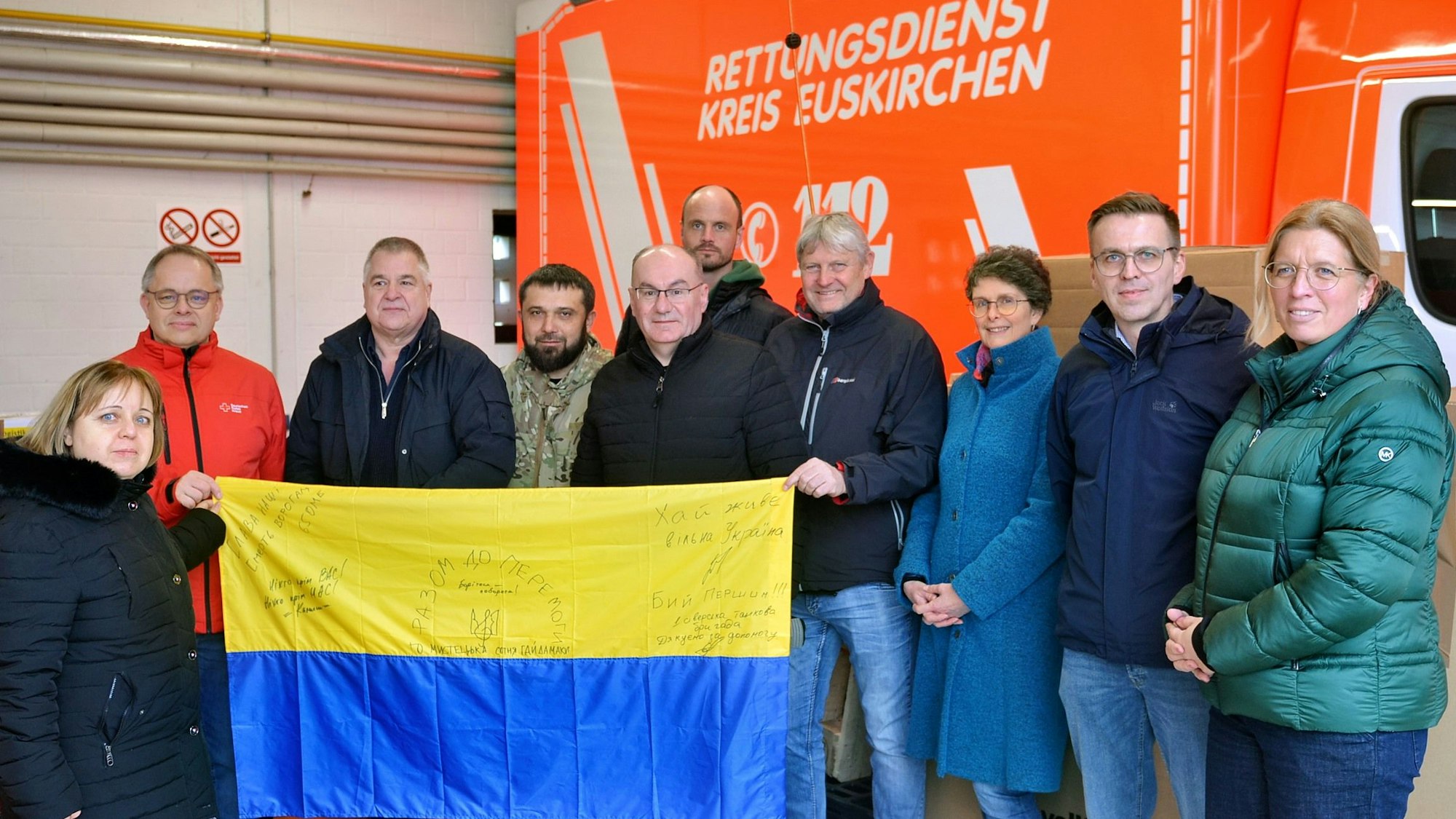 Oleksandr Popov und andere haben sich zu einem Foto aufgestellt. Sie halten eine Landesflagge der Ukraine ins Bild.