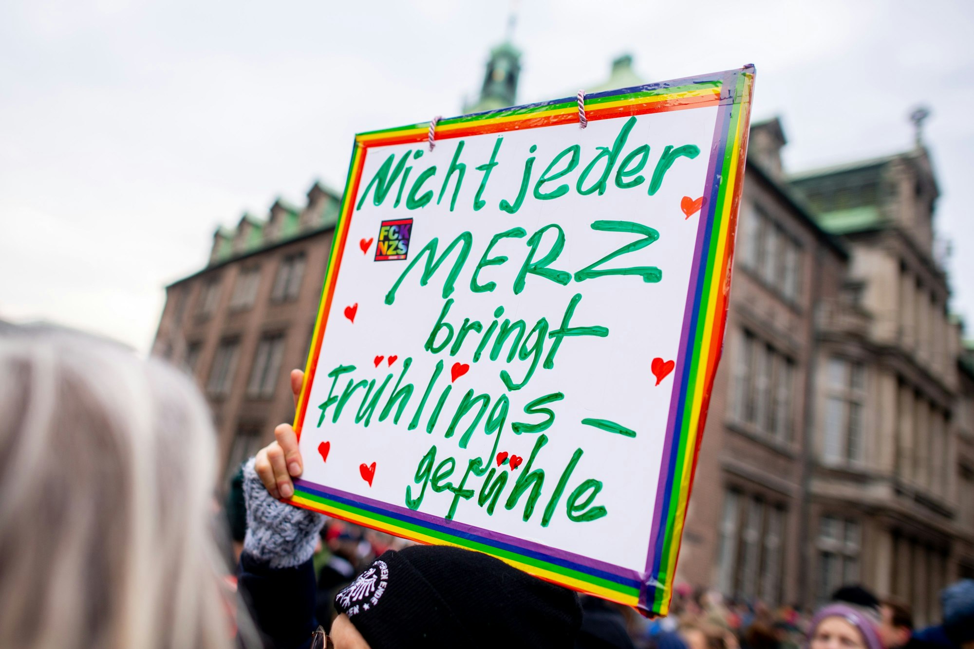 Eine Teilnehmerin demonstriert auf dem Domshof mit einem Schild mit der Aufschrift „Nicht jeder Merz bringt Frühlingsgefühle“ gegen Rechtsextremismus.