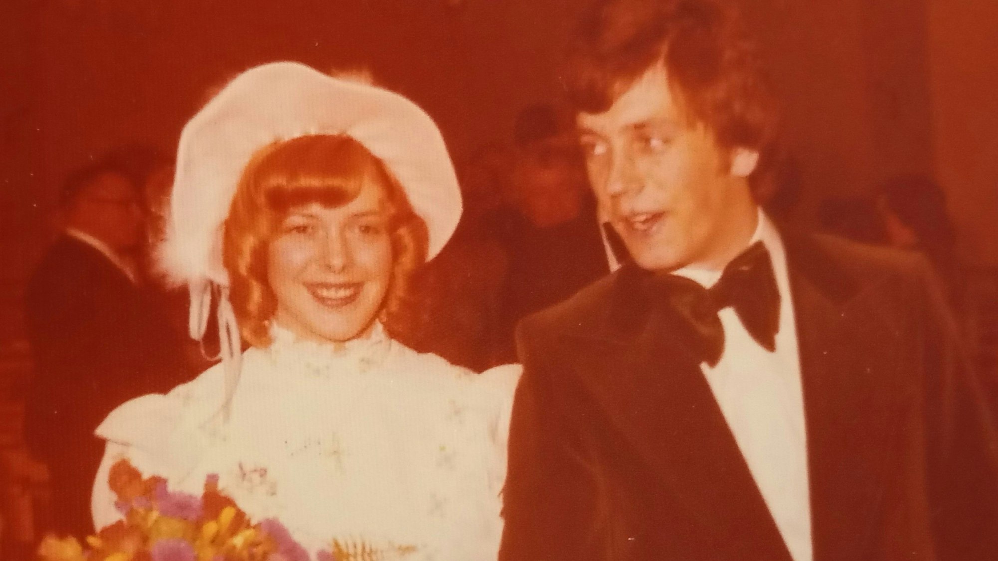Das Bild hat einen rötlichen Stich. Es zeigt das Paar, festlich gekleidet.