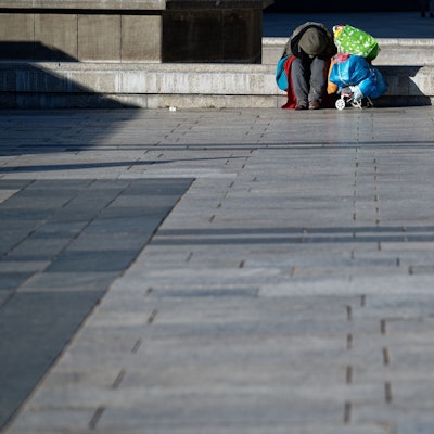 Ein Obdachloser wärmt sich auf dem Roncalliplatz vor dem Kölner Dom sitzend in der Sonne. (Symbolfoto)