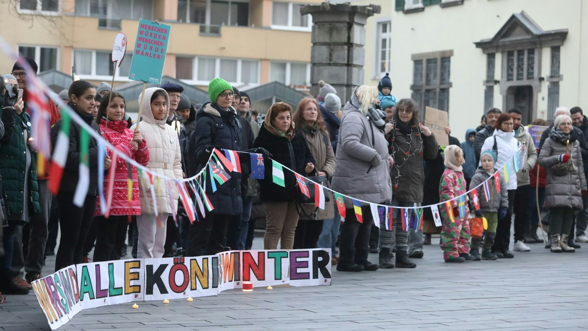 Eine Gruppe von Menschen, die eine Schnur mit den Flaggen vieler Nationalitäten halten.