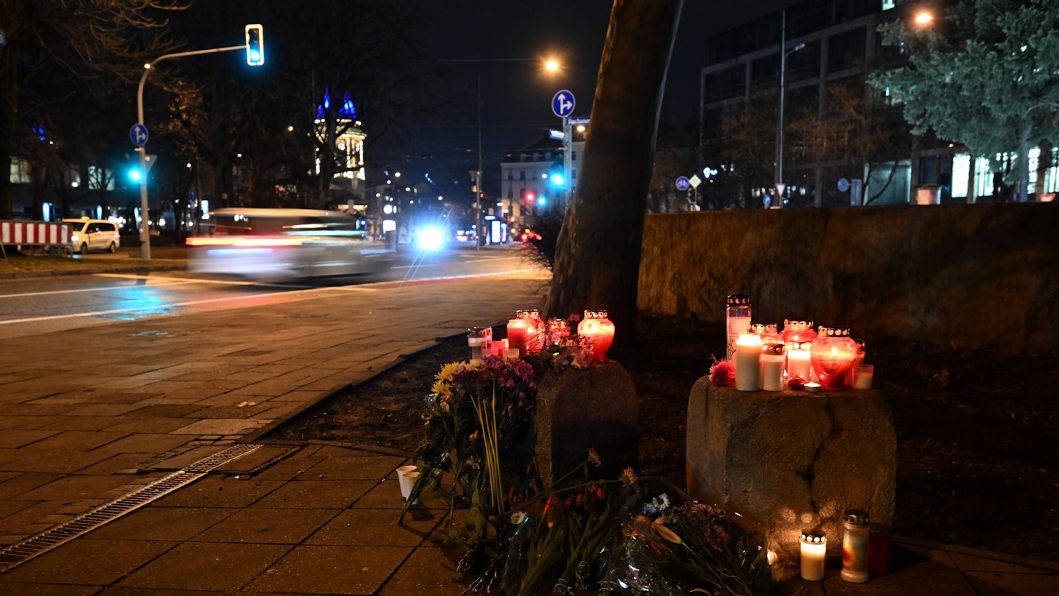 13.02.2025, Bayern, München: Blumen und Kerzen stehen in der Münchner Innenstadt in der Nähe des Stiglmaierplatzes, wo ein Auto in einen Demonstrationszug gefahren ist.
