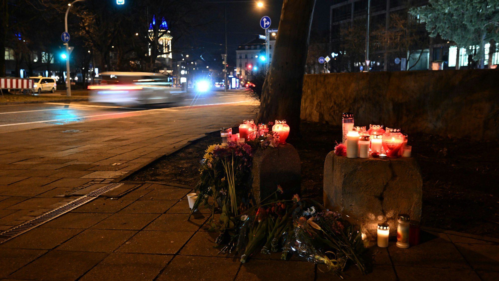 13.02.2025, Bayern, München: Blumen und Kerzen stehen in der Münchner Innenstadt in der Nähe des Stiglmaierplatzes, wo ein Auto in einen Demonstrationszug gefahren ist.