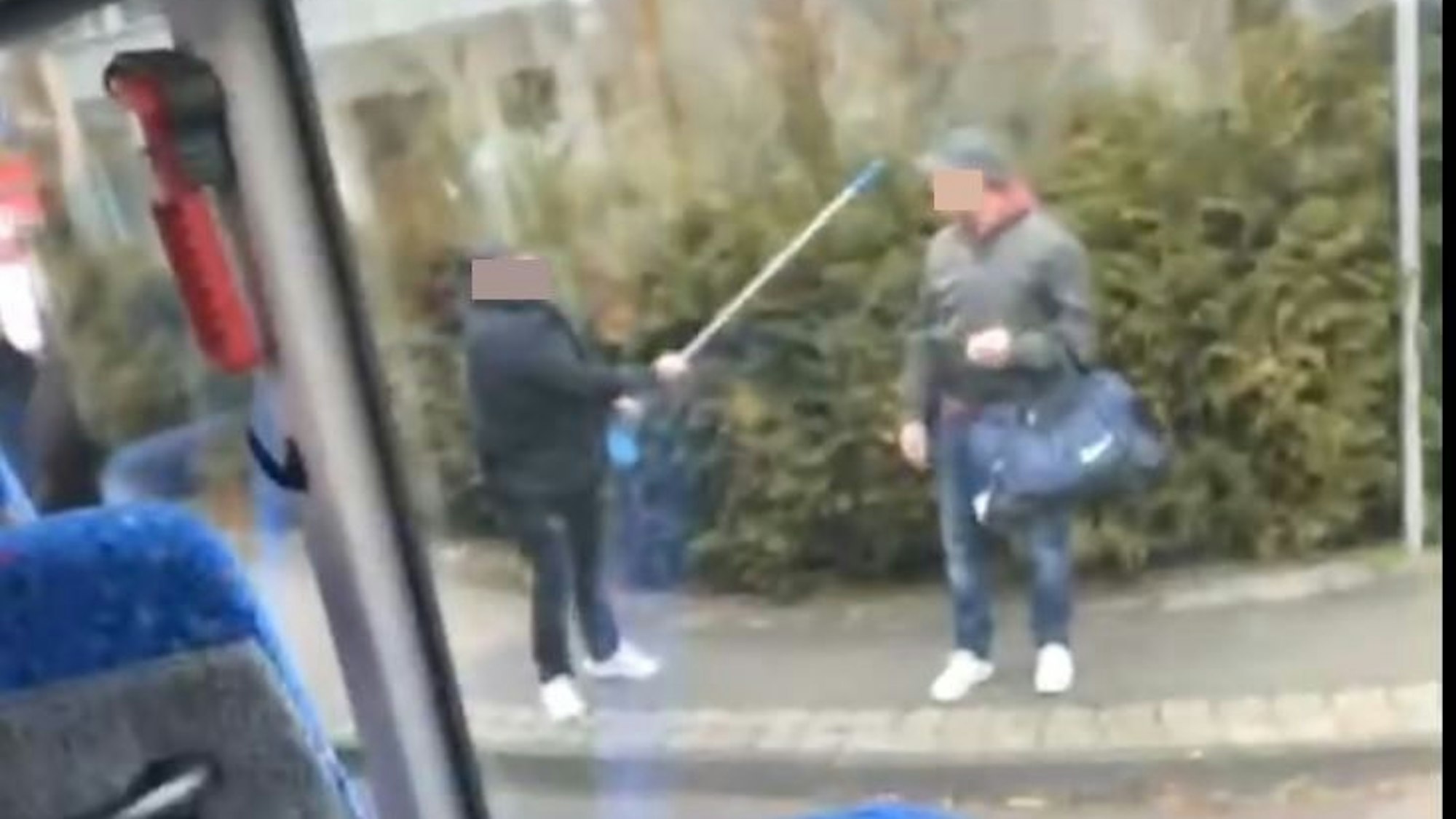 Ein dunkel gekleideter Mann hebt eine Krücke in Richtung eines anderen Mannes.