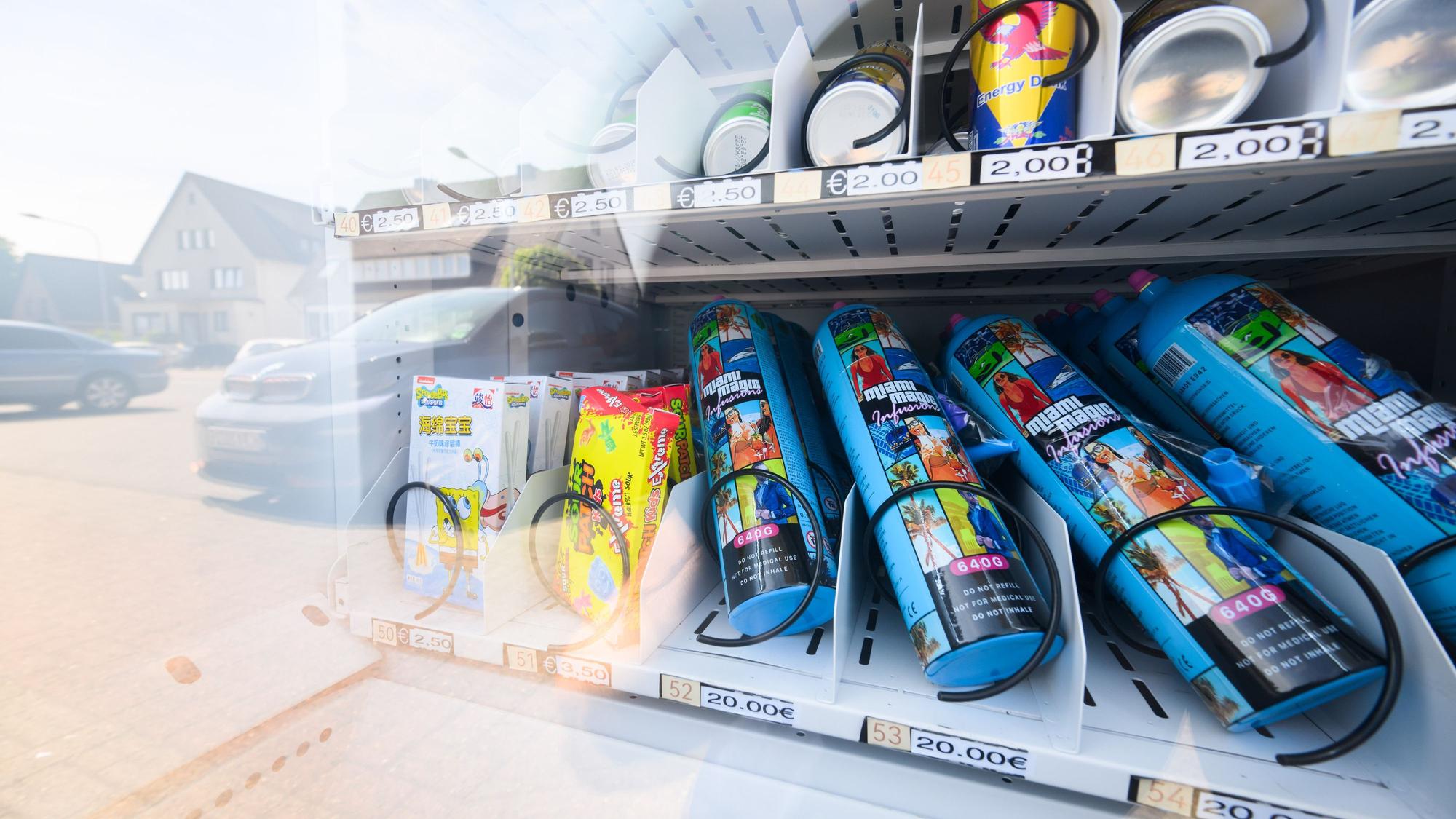 Ein Warenautomat, unter anderem mit Lachgasflaschen bestückt, steht vor einem Ladengeschäft.