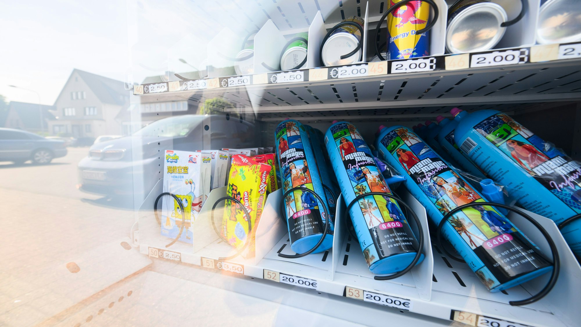 Ein Warenautomat, unter anderem mit Lachgasflaschen bestückt, steht vor einem Ladengeschäft.