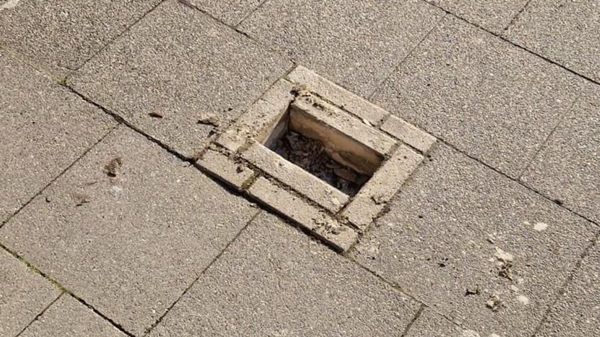 Zu sehen ist eine Lücke in einem Gehwegpflaster, in dem Steine fehlen.
