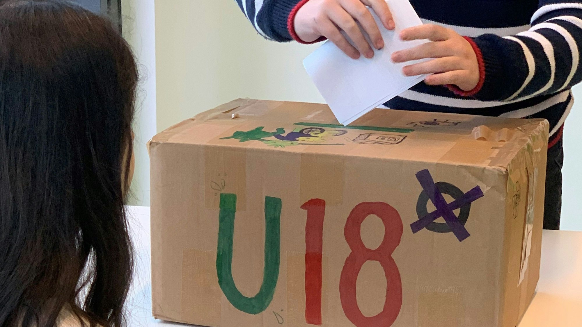 Die Stimmen für die U18-Wahl stecken die Schülerinnen in eine selbstgestaltete Urne.