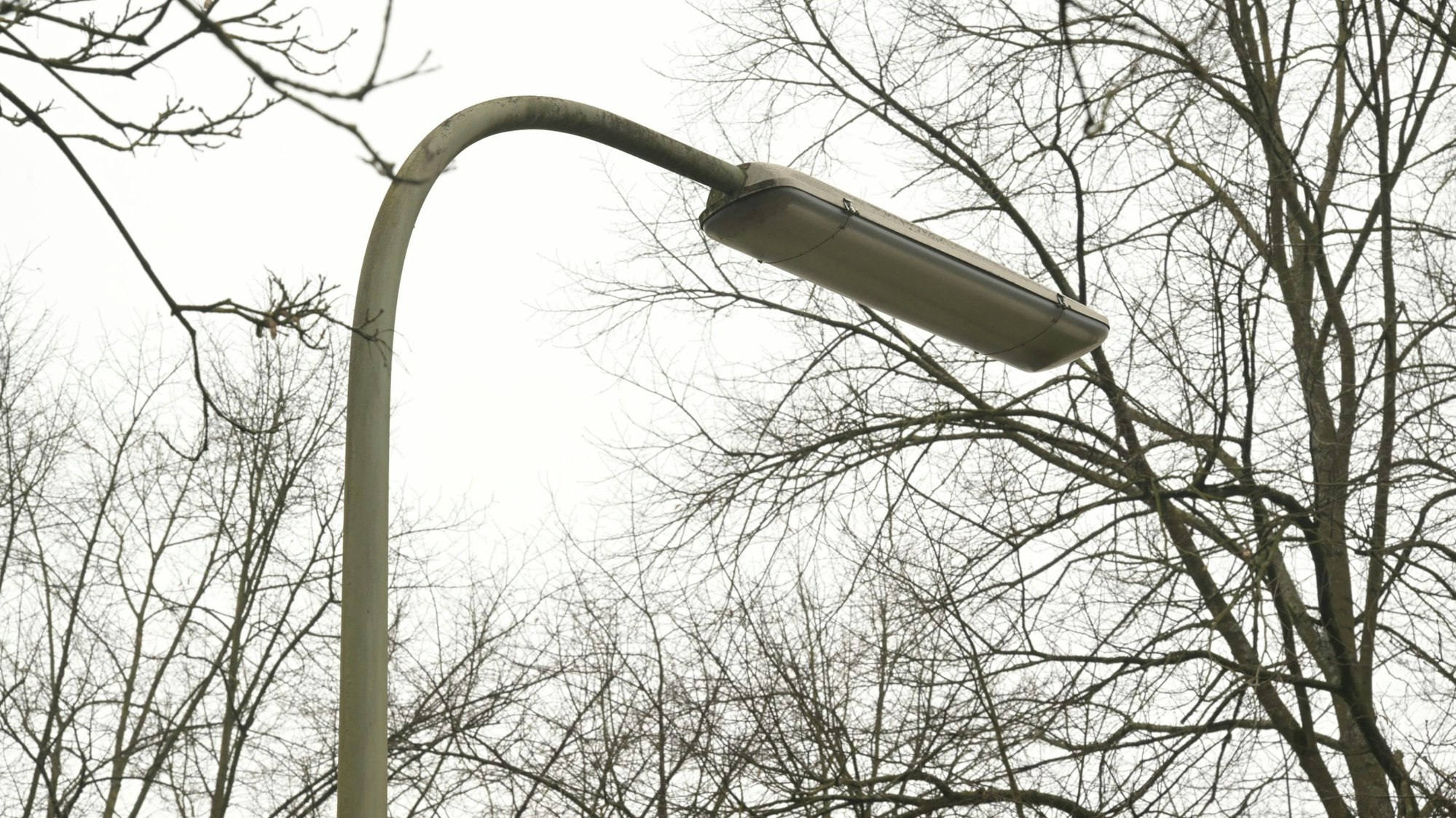 An einer Straße steht eine Straßenlampe in Bogenform.