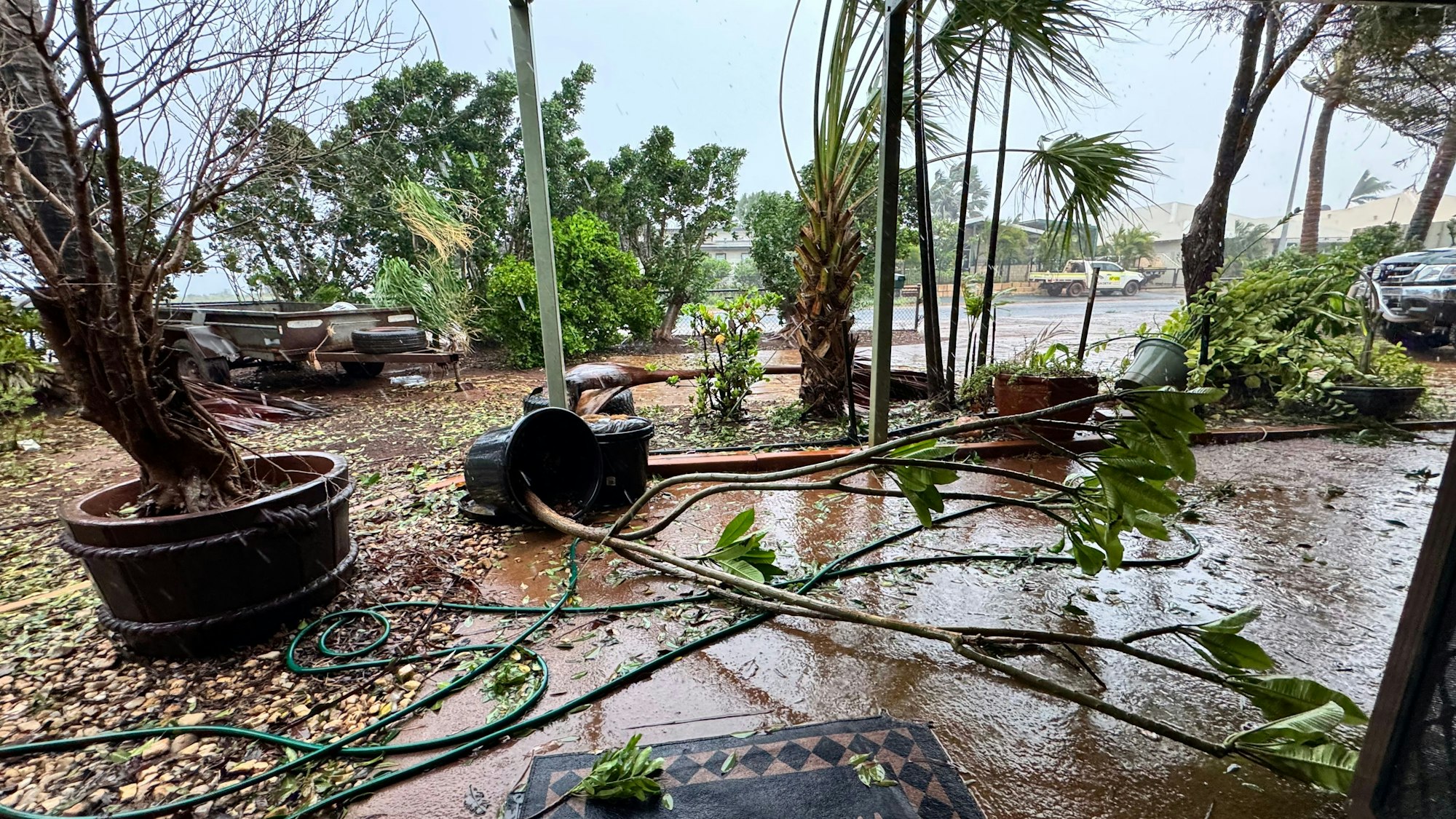 Die Aufnahme zeigt eine vom Sturm verwüstete Terrasse mit umgekippten Pflanzenkübeln und Ästen, die herumliegen.