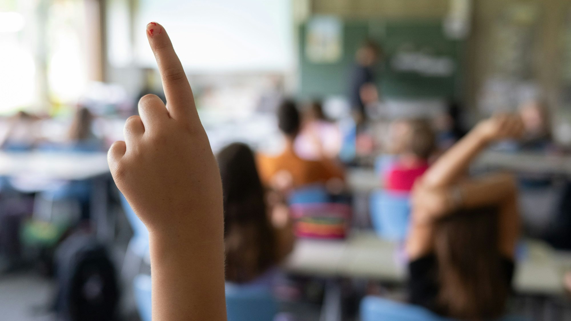 Schülerinnen und Schüler einer vierten Klasse einer Grundschule nehmen am Unterricht teil, eine Schülerin meldet sich. (Symbolbild)