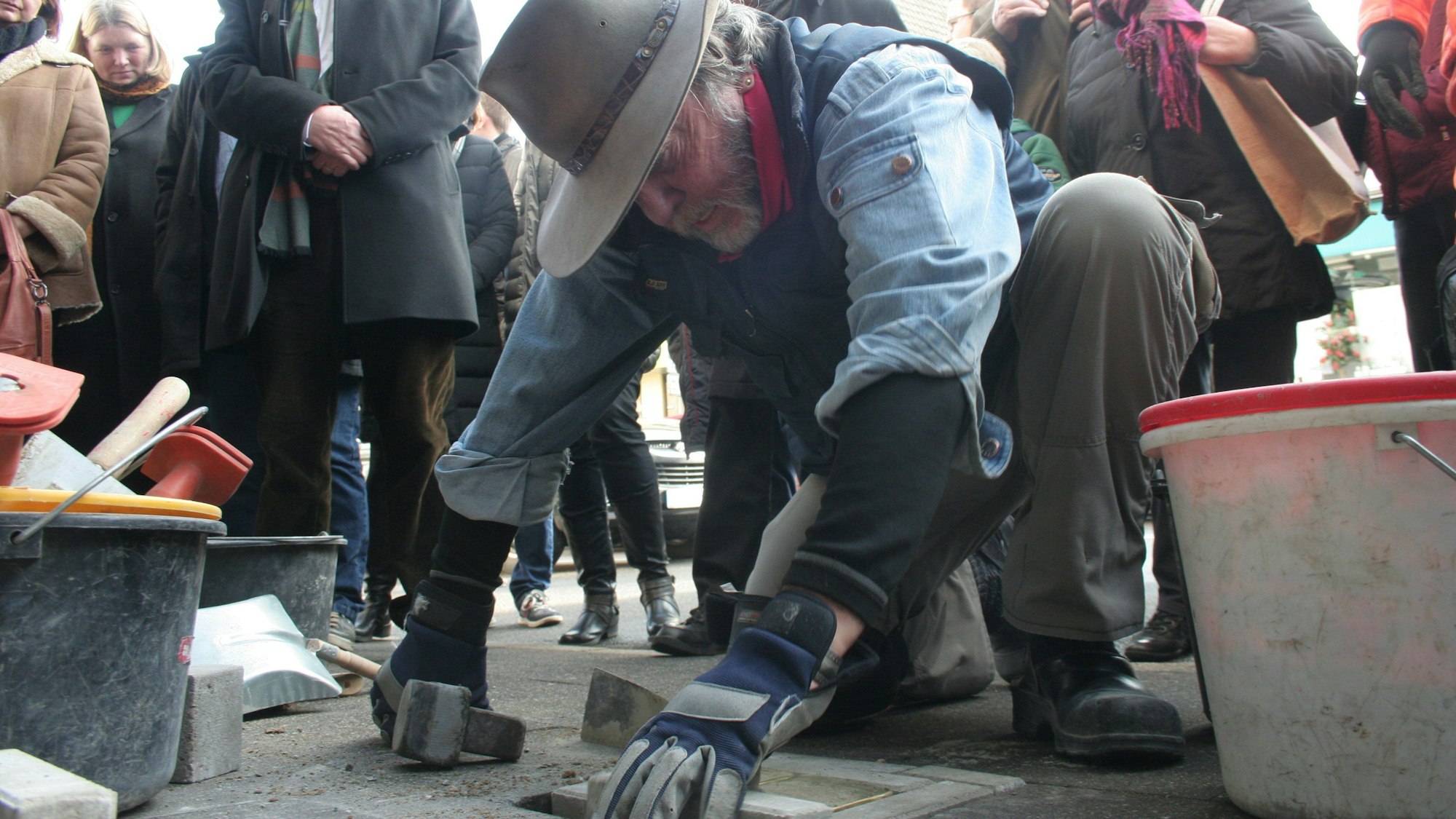 Zu sehen ist Künstler Gunter Demnig, der Stolpersteine verlegt.