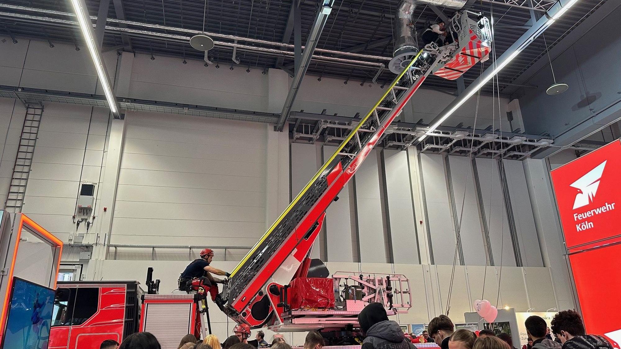 Ein Feuerwehrauto mit ausgefahrener Drehleiter in einer Halle