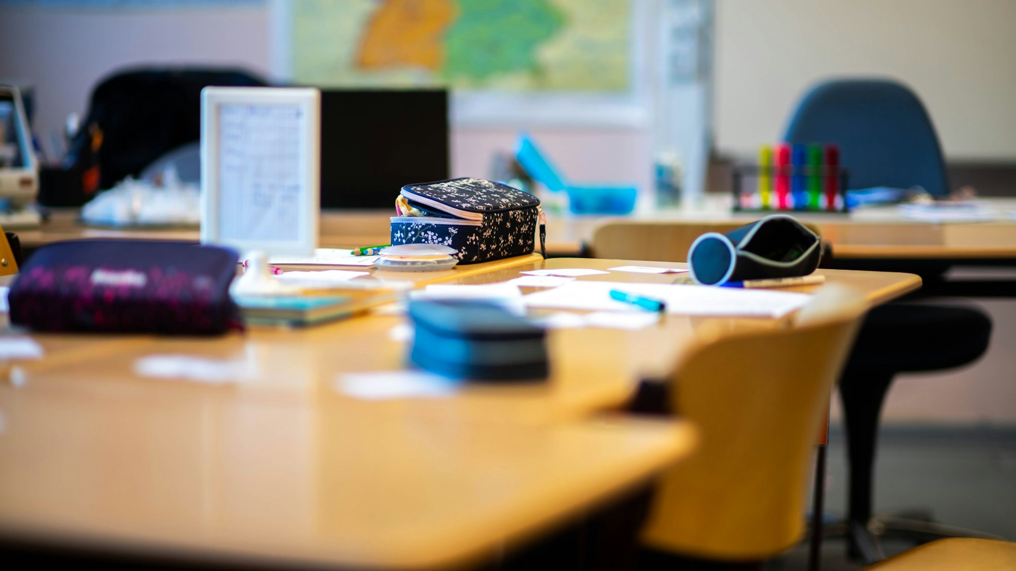 Das Bild zeigt einige Tische in einer Schule. Kinder sind nicht zu sehen.