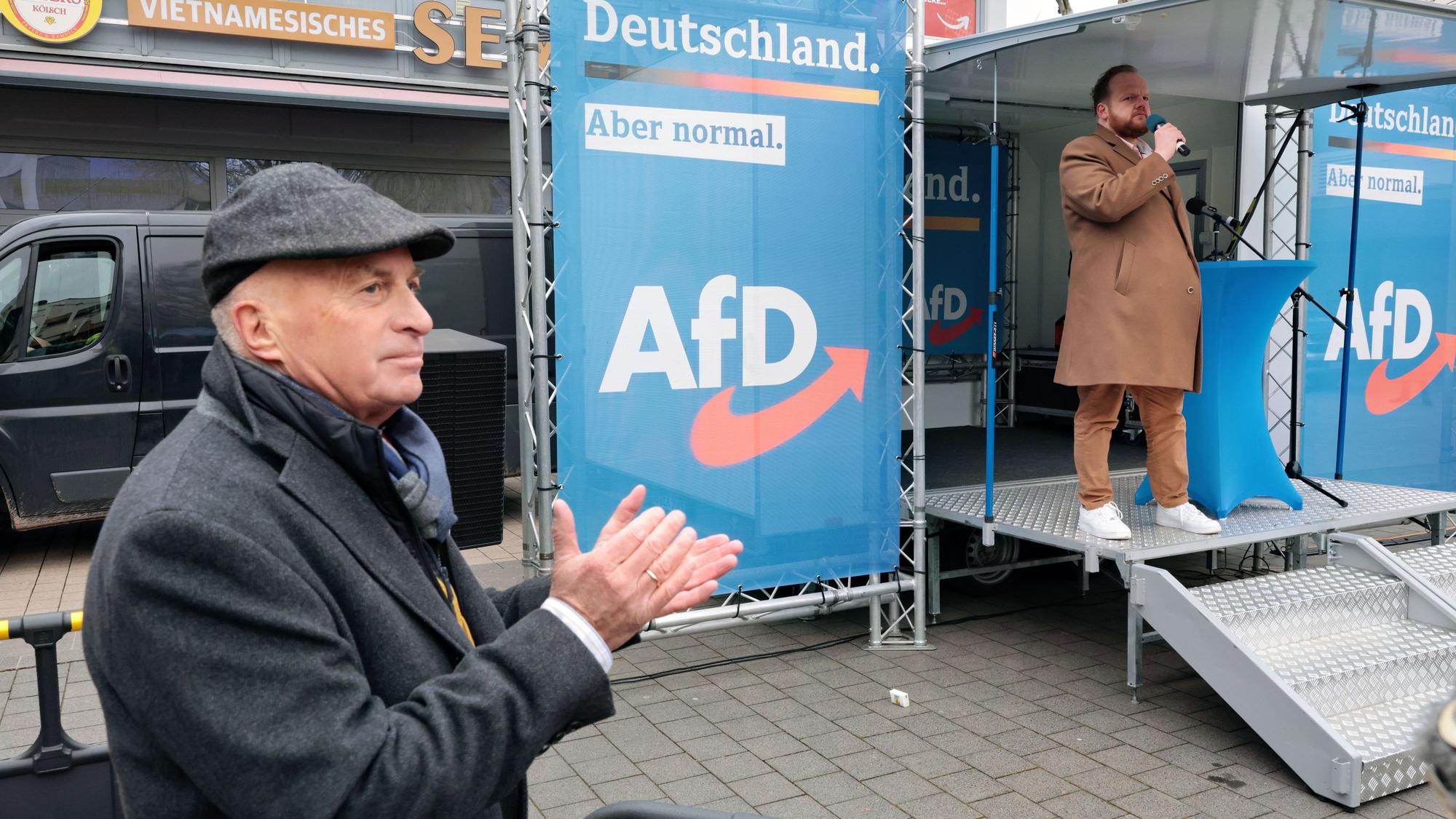 Der AfD-Bundestagsabgeordnete Rüdiger Lucassen steht neben einer Bühne, auf der Sven Tritschler spricht, und applaudiert.