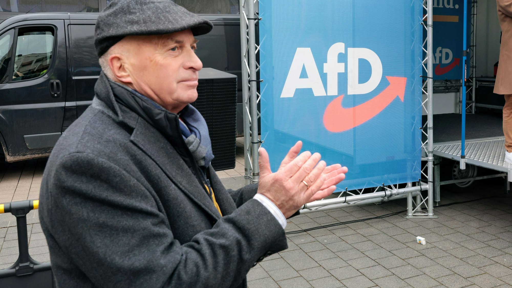 AfD-MdB Rüdiger Lucassen applaudiert neben einem Banner mit dem AfD-Emblem.