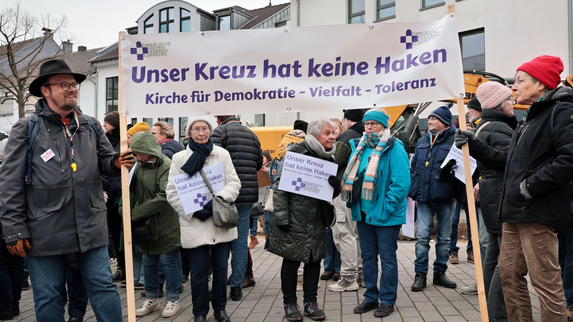 Teilnehmer der Demonstration in Euskirchen für Freiheit und Demokratie halten ein weißes Transparent, auf dem steht „Unser Kreuz hat keine Haken. Kirche für Demokratie, Vielfalt, Toleranz“.