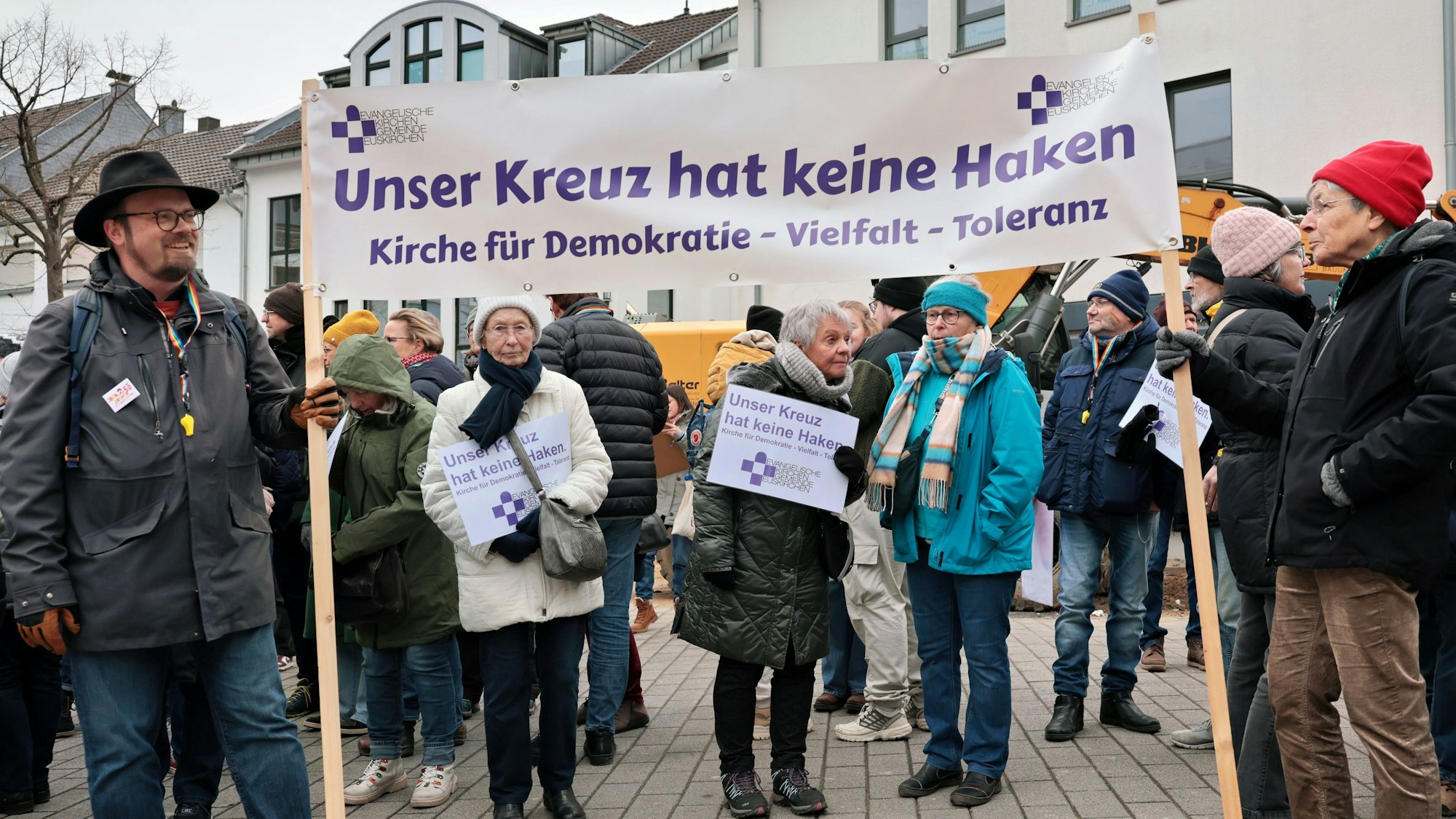 Teilnehmer der Demonstration in Euskirchen für Freiheit und Demokratie halten ein weißes Transparent, auf dem steht „Unser Kreuz hat keine Haken. Kirche für Demokratie, Vielfalt, Toleranz“.
