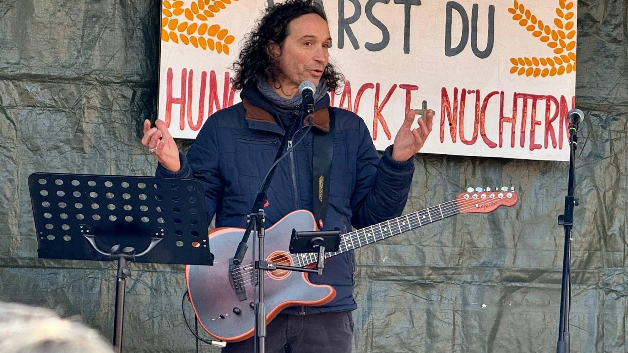 Ein Mann steht mit einer Gitarre auf einer Bühne.