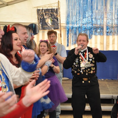 Um einen Mann mit Mikrofon stehen Menschen, die klatschen.