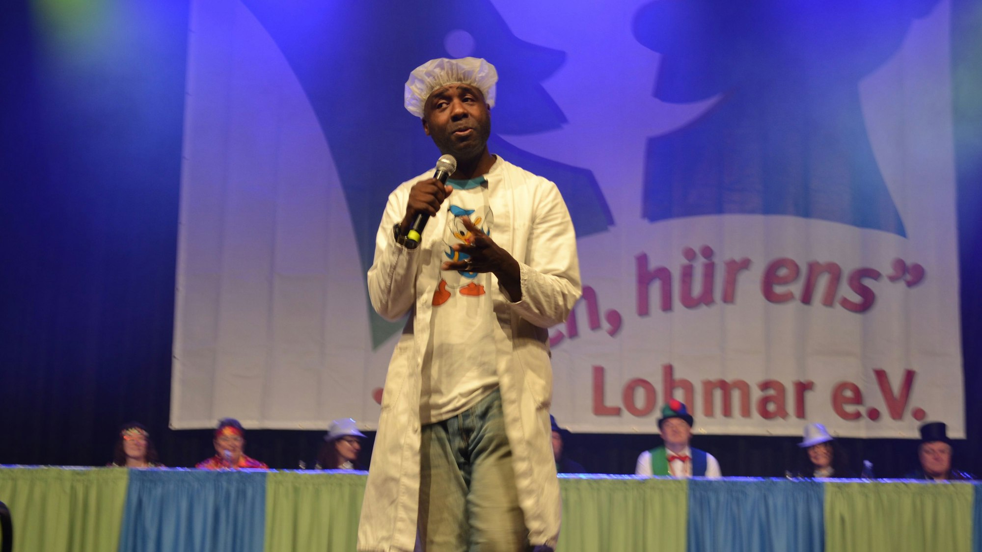 Ein Mann steht bei einer Karnevalssitzung auf der Bühne