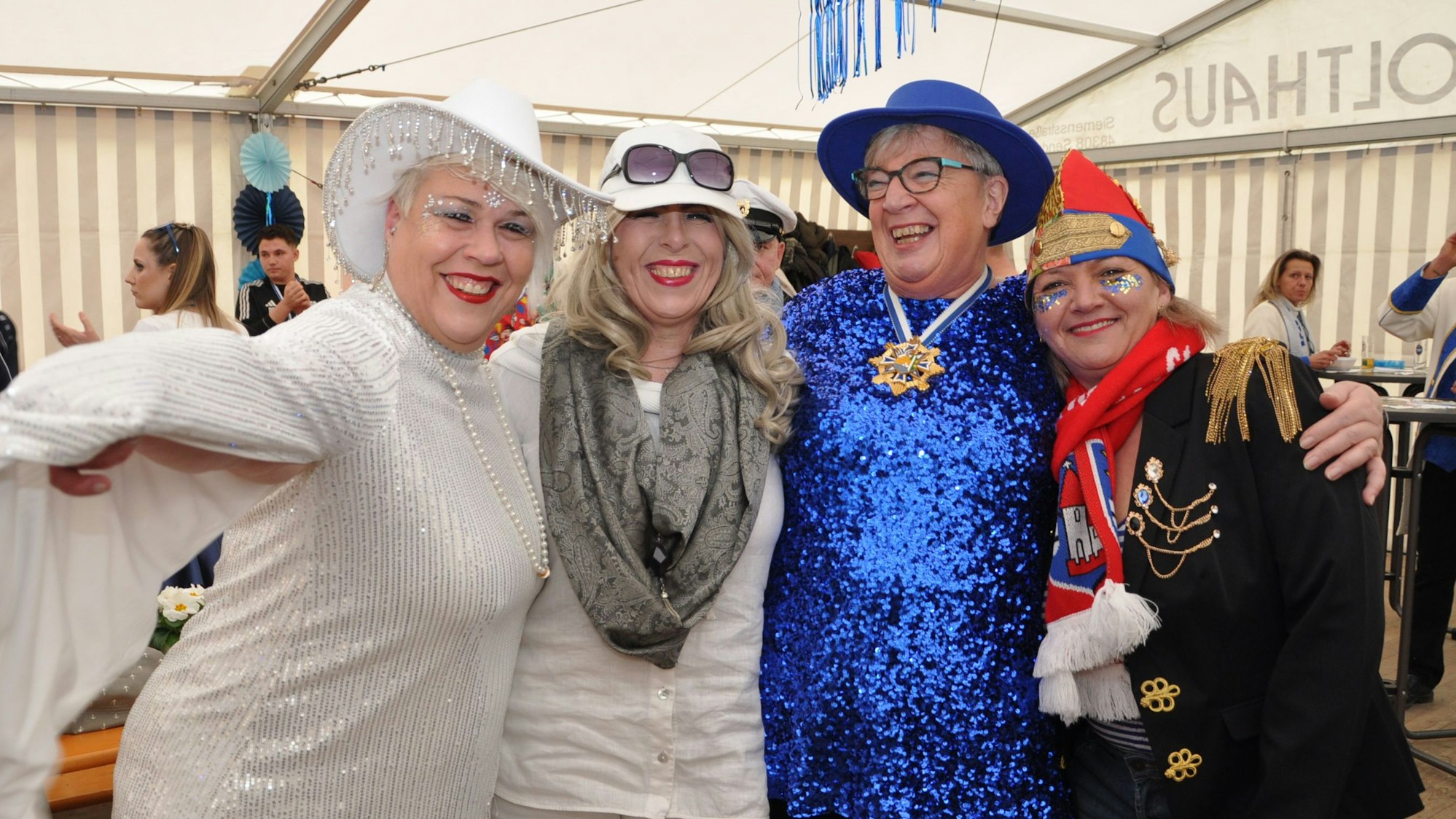 Kostümierte Menschen halten sich in den Armen und lachen.