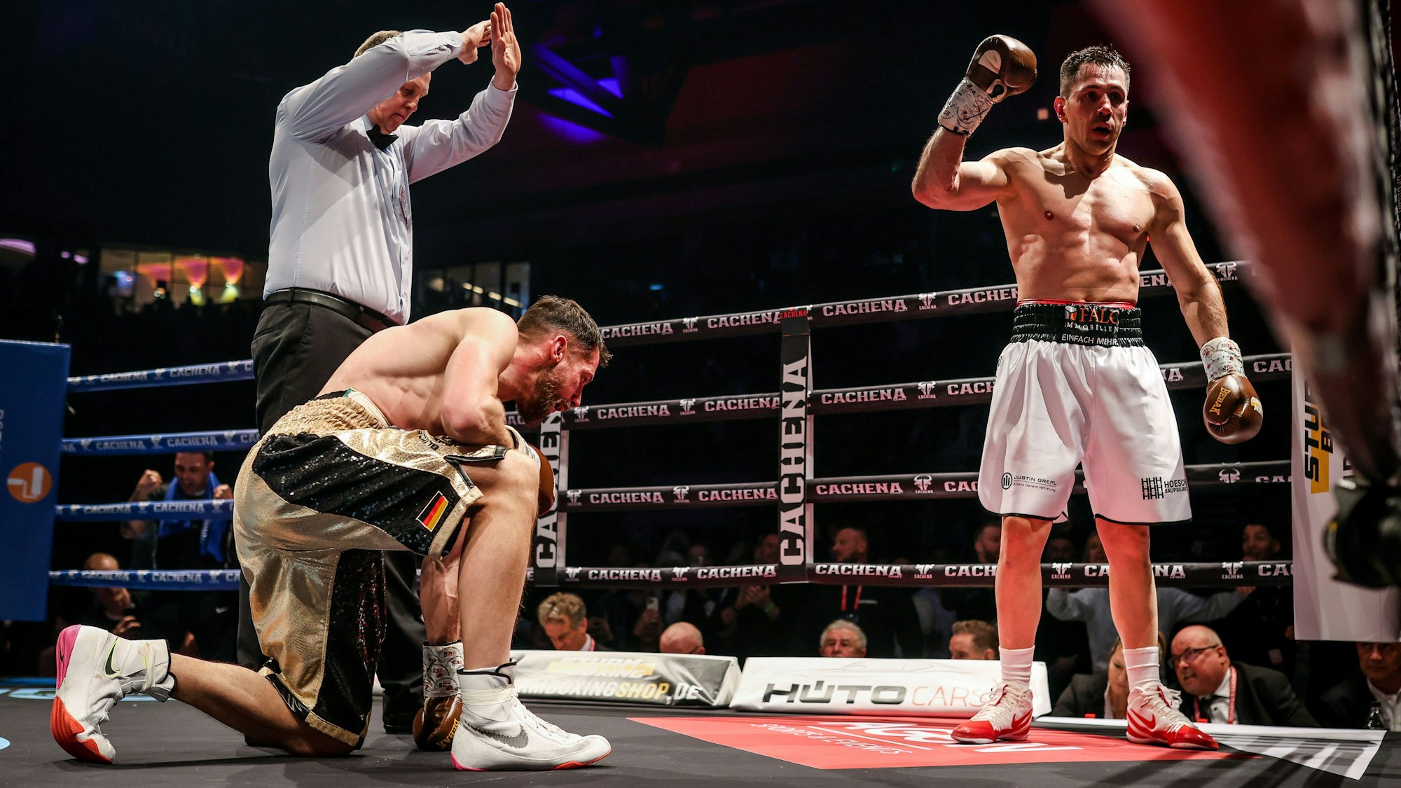 Felix Sturm hebt die Faust, während sein Gegner Benjamin Blindert auf dem Boden kniet und der Kampf vom Schiedsrichter als beendet erklärt wird.