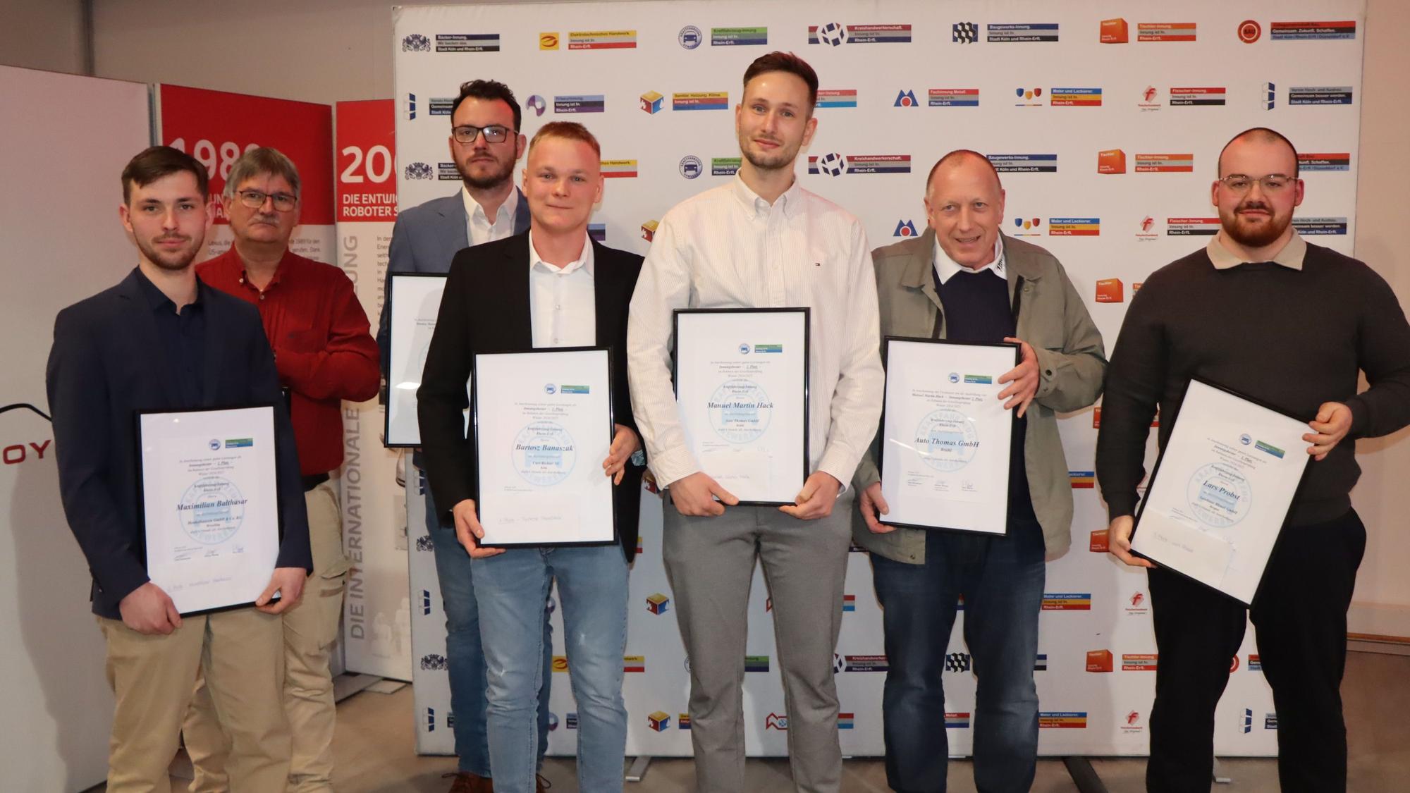 Männer mit Urkunden stehen nebeneinander.