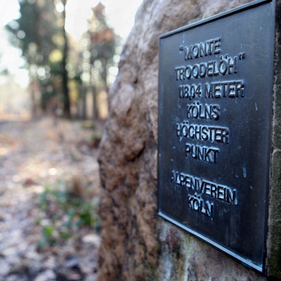 Am Weg steht eine Stein mit einer Bronzetafel auf dem Gipfel des Monte Troodelöh.