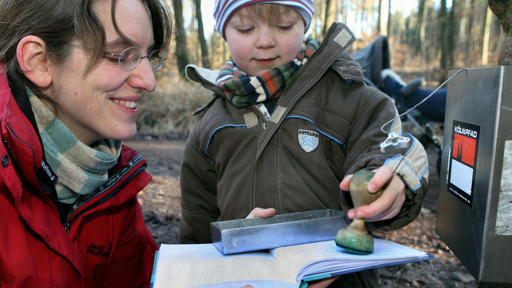 Ein Kind drückt einen Stempel in das Gipfelbuch des Monte Troodelöh im Königsforst.