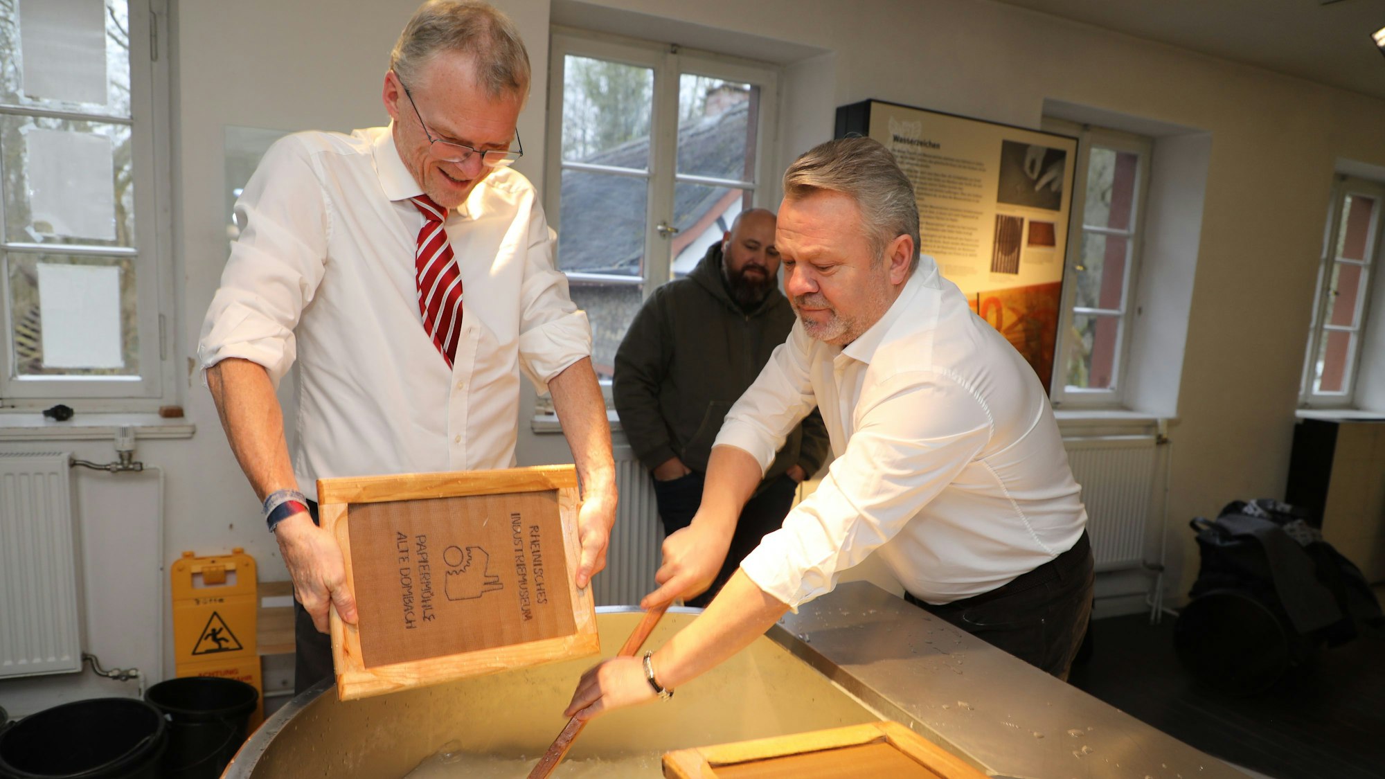 Butschas Bürgermeister Anatolii Fedoruk und Bergisch Gladbachs Bürgermeister Frank Stein schöpfen Papier im LVR-Industriemuseum Papiermühle Alte Dombach.