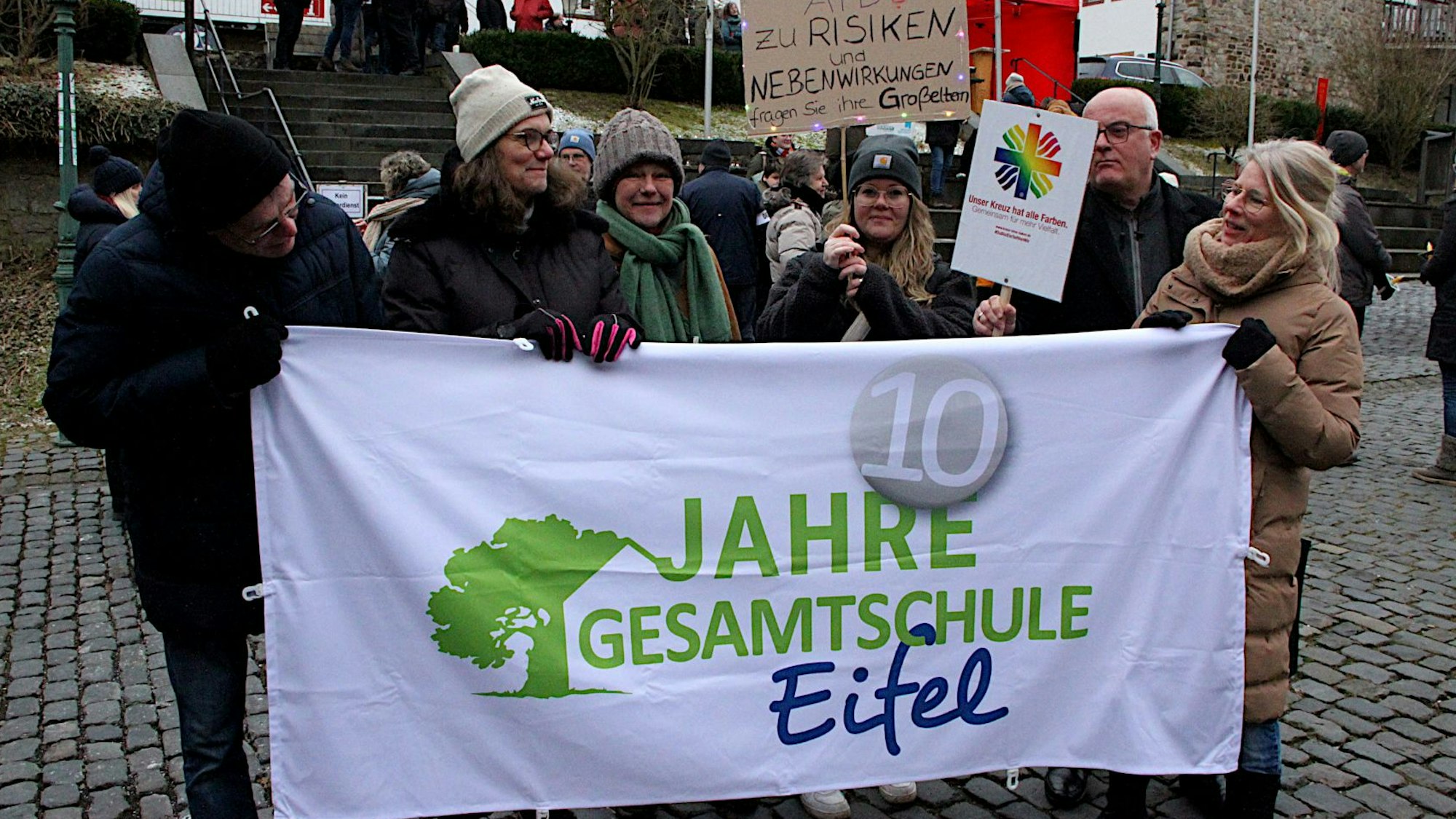 Schüler und Lehrer tragen ein Banner, auf dem zu lesen ist: „Zehn Jahre Gesamtschule Eifel“.