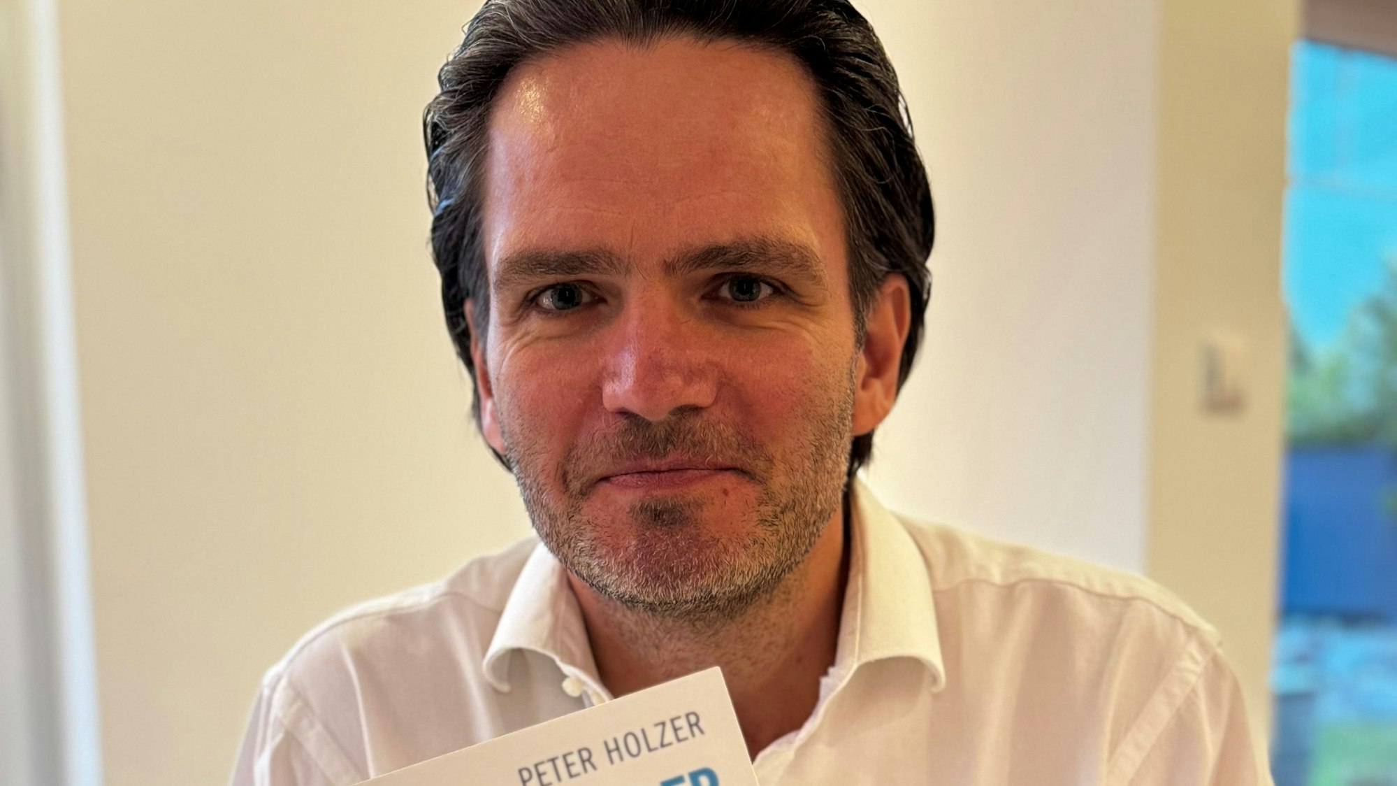 Auf dem Bild ist das Portrait eines Mannes mit einem Buch in der Hand zu sehen.